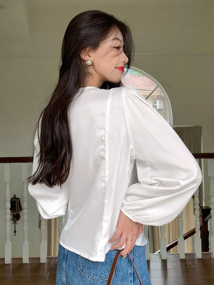 Blusa de satén con botones y mangas de linterna con cuentas de perlas