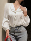 Blusa de satén con botones y mangas de linterna con cuentas de perlas